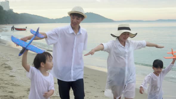 Happy asian family having fun and cheerful with straightened arm same a plane on the beach. alt