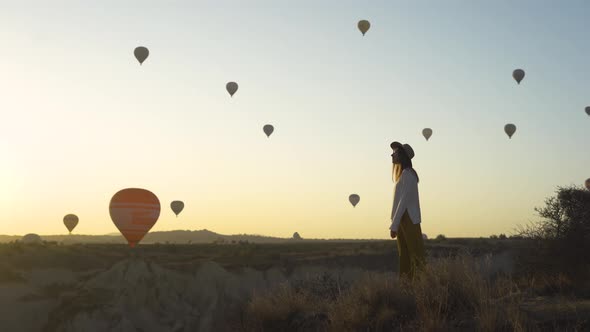 Woman Watching the Sunrise and Hot Air Balloons