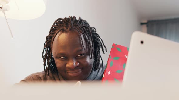 Emotional Black Man Showing Gift on Video Call alt