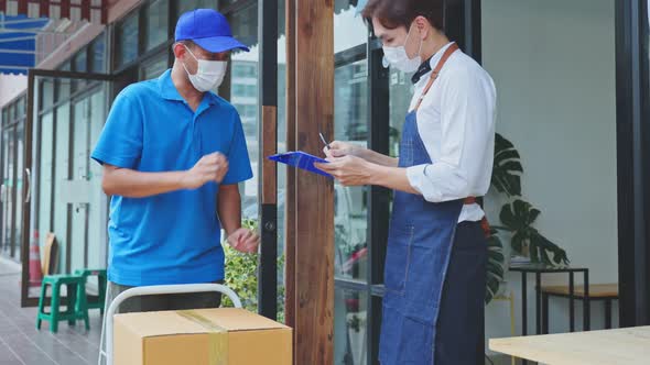 Asian Postman deliver food ingredient box to restaurant waiter in cafe. alt