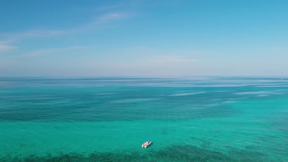 Aerial footage of drone flying over turquoise waters away from boat in Cayman Island alt