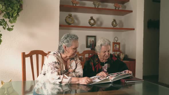 Aged women examining photos together alt