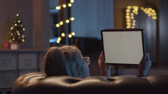 Back View of Woman Laying on Sofa Watching a Movie on Her Digital Table alt