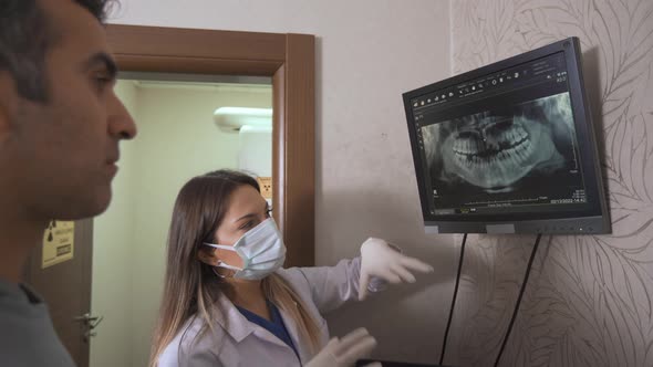 Dentist gives information to his patient via x-ray. alt