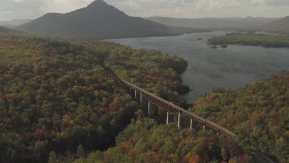 A mountain and railroad trestle on the shore of a wind blown lake during early fall golden hour AERI alt