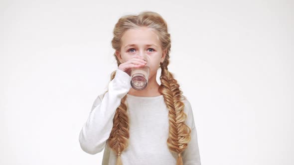 Young Adorable Caucasian Girl with Luxurious Long Blonde Hair Drinking Water From Glass on White alt