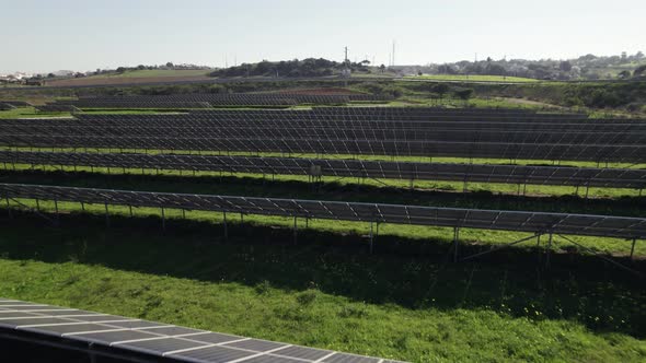 Solar energy production farm, flying low over photovoltaic panels on grass field, Lagos