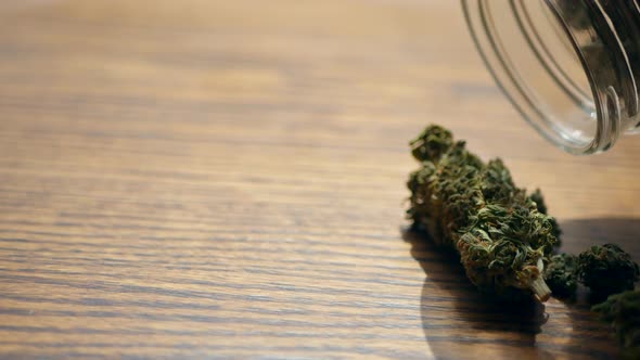 Marijuana poured out of glass jar for recreational or prescription medicinal weed smoking alt