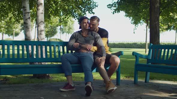 Romantic Same-sex Male Couple Cuddling on Park Bench alt