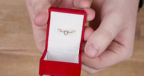 Hands of a Male Opening a Wedding Ring Box Before Proposal alt