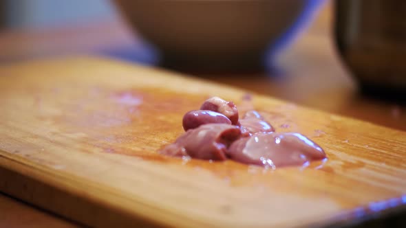 Woman Chef Slices Chicken Liver Meat on a Wooden Kitchen Board in Home Kitchen. alt