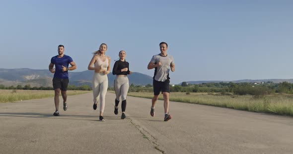 Multiethnic Group of Athletes Running Together on a Panoramic Countryside Road alt