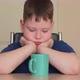 A Fat Child is Sitting at the Table Propping His Chin on His Hands Looking at a Mug - VideoHive Item for Sale