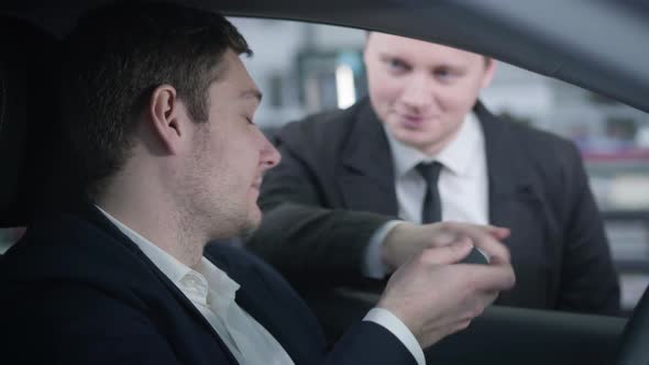 Close-up Side View of Confident Caucasian Man Taking Car Keys From Dealer and Starting Engine alt