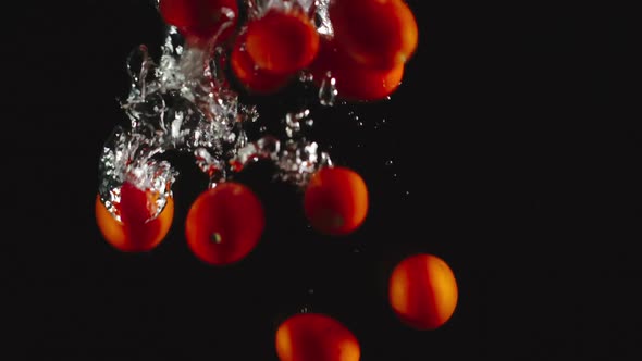 Cherry Tomatoes Fall Under Water On Black Background