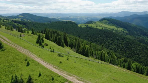 Aerial Drone View of a Country Road Through Green Hills of Wooded Mountains alt