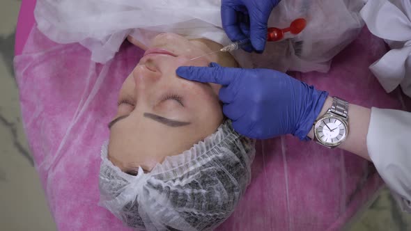 The Beautician in the Gloves Makes a Correction of the Nasolabial Folds