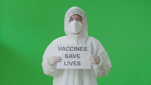 Asian Man Wear Protective Uniform PPE And Holding Vaccines Save Lives Sign In Green Screen Studio alt