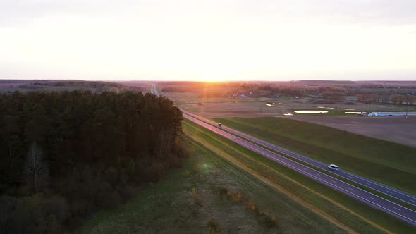 Aerial Over Intercity Distance Paved Highway Passing Through Fields At Sunset alt