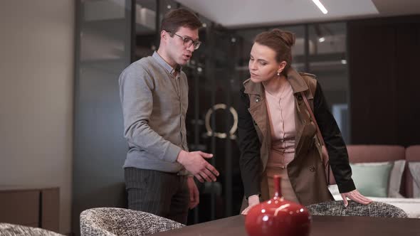 Male Expert Talking Explaining Furniture Set Quality As Wealthy Woman Touching Furnishings in alt