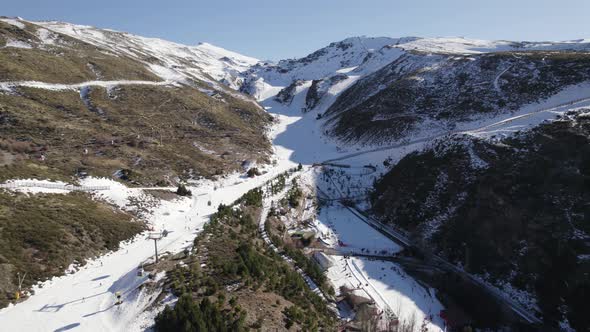 Drone flying over ski slopes and cableway, Sierra Nevada in Spain. Aerial reverse