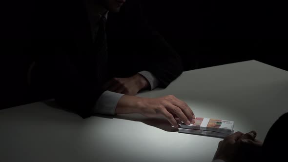 Businessman rejecting money offered by his partner in the dark, anti bribery concept