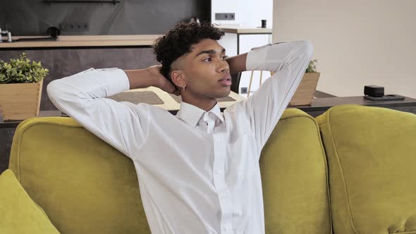 Calm Young Afroman in White Shirt Having Healthy Daytime Nap Dozing Relaxing on Couch with Eyes alt