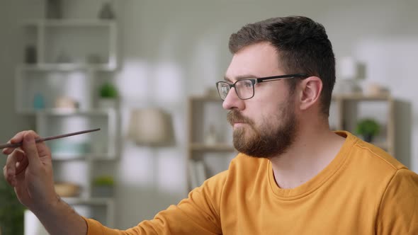 Young Man is Working in His Modern Home Studio in the Morning Drawing on Canvas Enjoying the Process alt