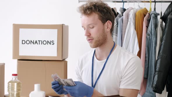 Young Volunteer Checking Clothes Donation Box and Making Notes Humanitarian Aid alt