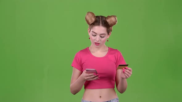 Teenager with a Credit Card and a Phone in His Hands. Green Screen. Slow Motion alt