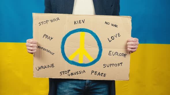 Boy Holds Cardboard with Peace Symbol for for the War in Ukraine alt