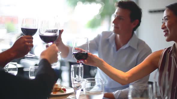 Friends clinking glasses of red wine in restaurant