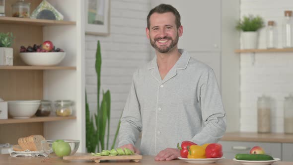 Young Man Doing Video Call on Smartphone While Standing in Kitchen alt