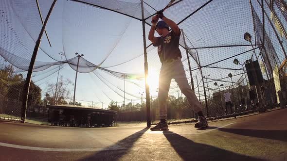 A baseball player practicing at the batting cages. alt