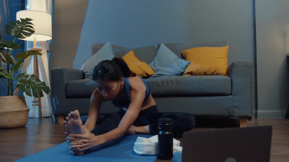 sia lady in sportswear exercises doing work out and using laptop to watch yoga video tutorial.