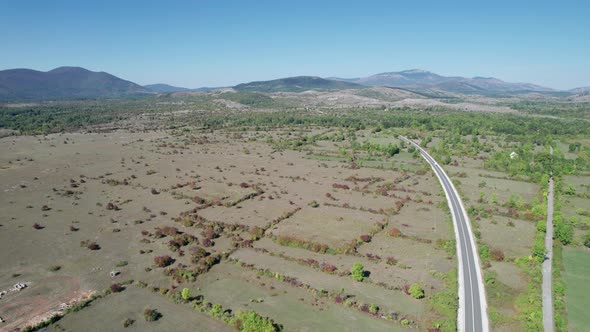 Aerial View Empty Asphalt Road on the Plateau Between Green Fields Highland Way alt