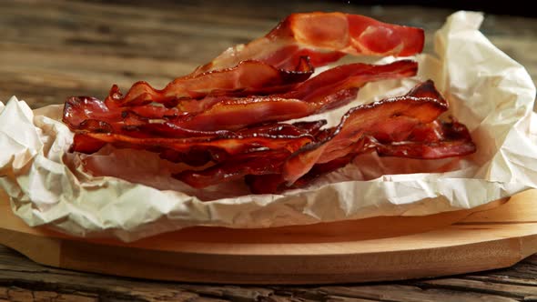 Super Slow Motion Shot of Roasted Bacon Slices Falling on Crumplet Paper at 1000 Fps. alt