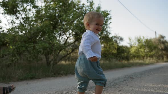 Cute Toddler Walks on Road Turning and Looking at Camera alt