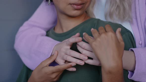 Close Shot of Young Girl Hugging Her Girlfriend Playing with Hands and Kissing