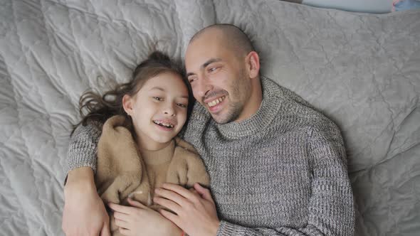 Father and Daughter Laughing and Bonding in Bed