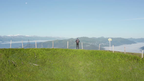 Man Controlling a Drone By the Schwalbenwand Peak with Foggy Horizon in View alt