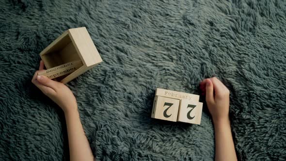 Hands of a boy flip over wood wooden cubes. Wooden cube calendar alt