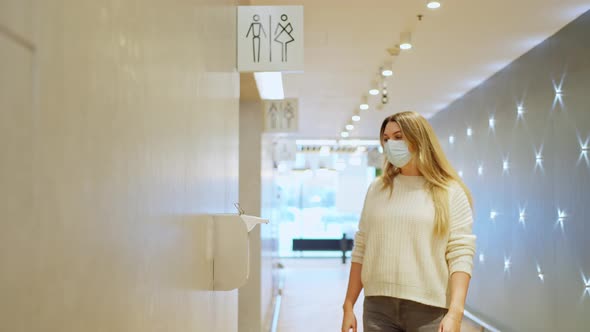 Woman in a Protective Mask Comes Out of WC Liquid Alcohol Hand Sanitizer alt