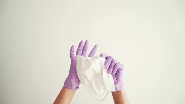 Woman Hands in Latex Protective Gloves Holding a Facial Medical Mask alt