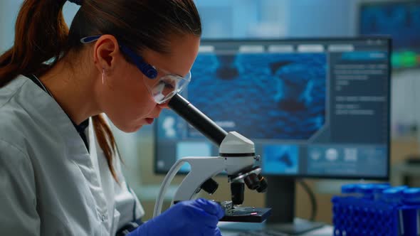 Portrait of Scientist Looking Under Microscope in Medical Lab alt