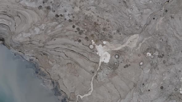 Extreme long shot, satellite view, dead sea shore, flood stream and sinkholes alt