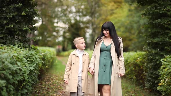 Mom and Son are Walking in the Park in Autumn