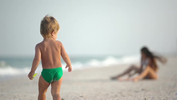 Older Sister Playing with Younger Brother Aground Near the Shore on Summer Vacation alt