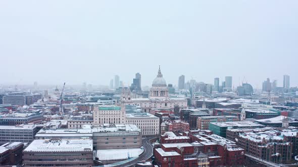 descending aerial drone shot of St Pauls cathedral snowing City of London alt