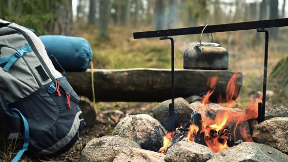 Backpack and Metal kettle on a campfire in the forest